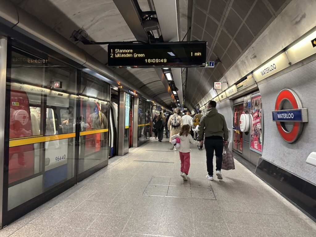 Subway station with passengers, trains, and display board in a tunnel.