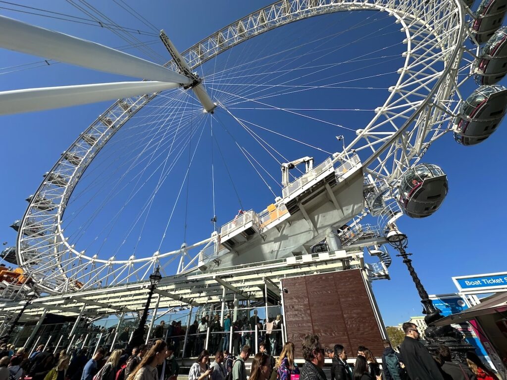 The London Eye Ferris wheel with passenger cabins and visitors at the foot of the wheel.