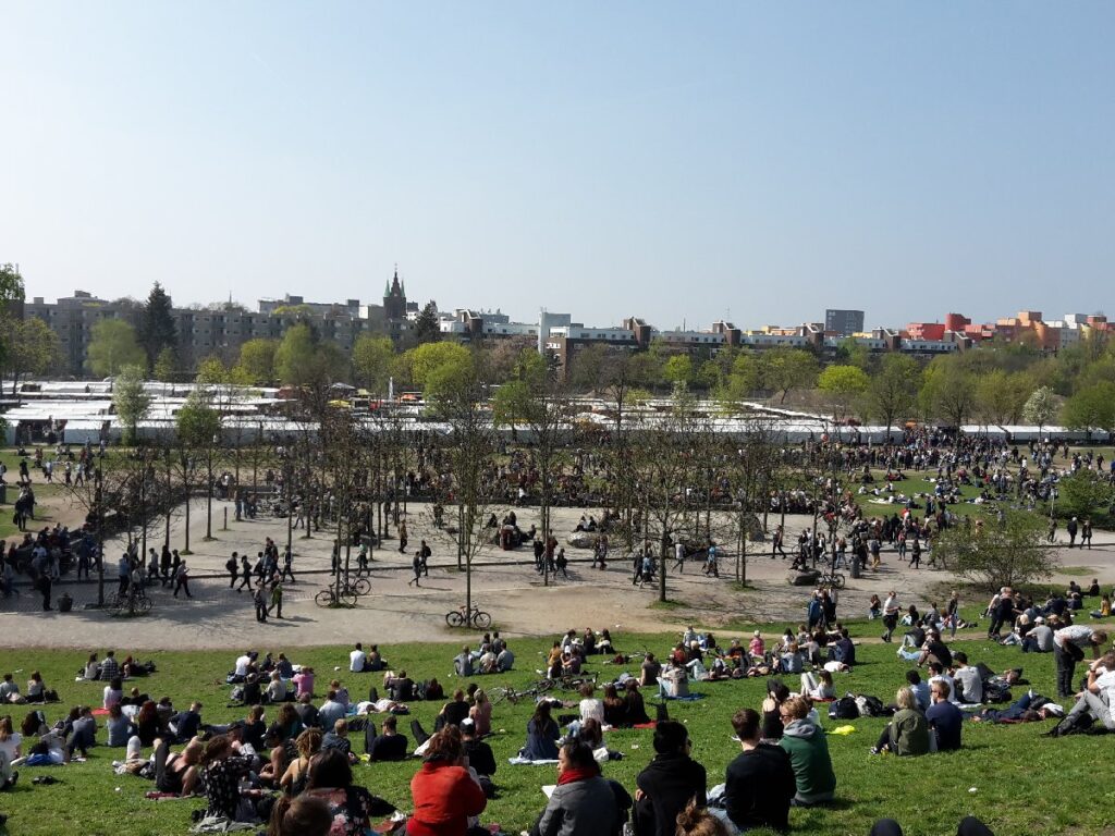 Visitors relax on the grassy slopes and walk among the trees at Mauerpark during a busy Sunday flea market in Berlin.