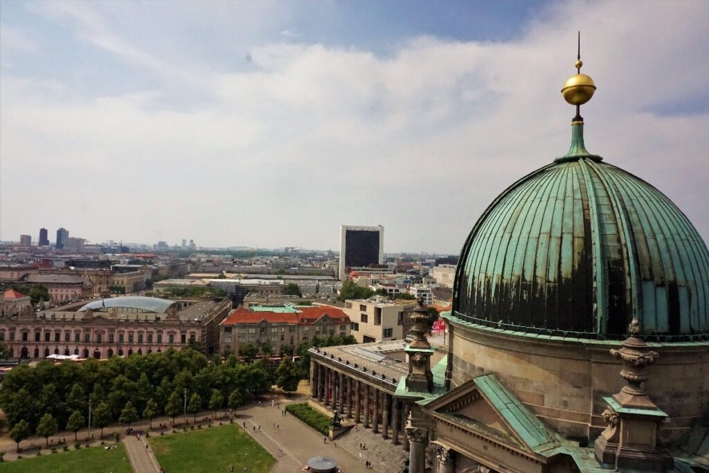 Berlin Cathedral’s green copper dome rises above the rooftops, with Museum Island and central Berlin stretching beneath a cloudy sky.