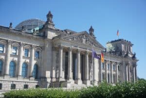 A view of the Reichstag’s columned stone facade, with its glass dome and German flags above the entrance in Berlin.